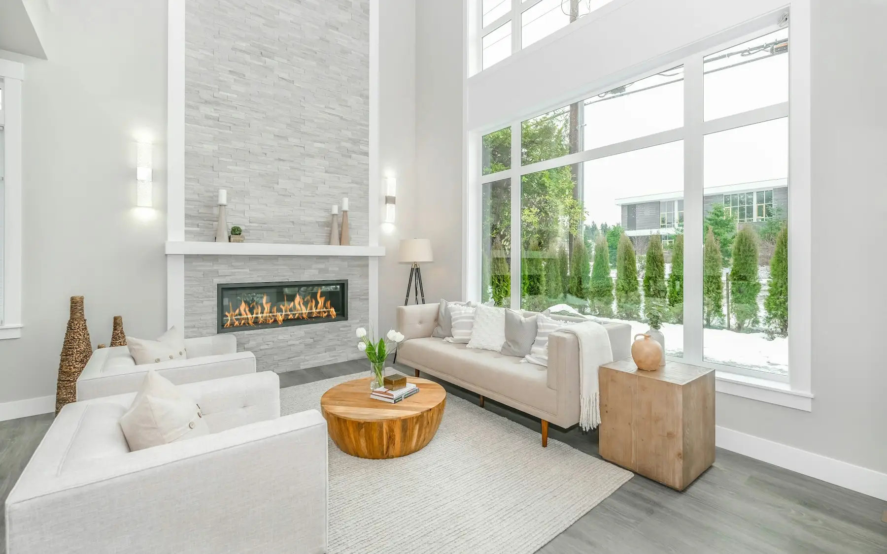 Living luminoso de doble altura con grandes ventanales y chimenea
